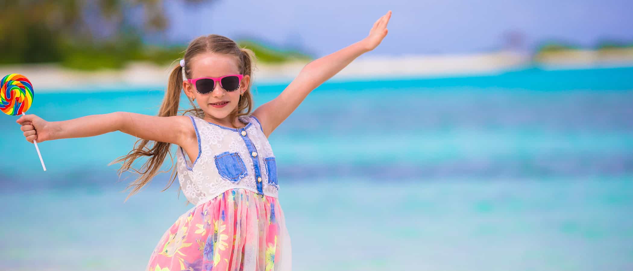 Adorable little girl with lollipop on white beach