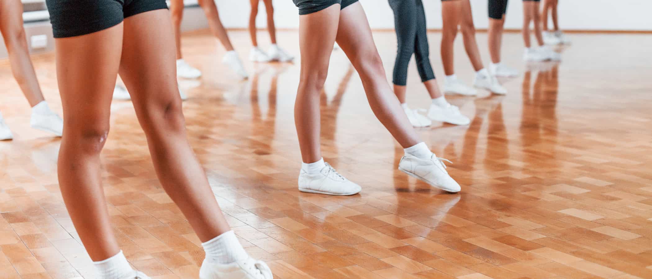 Standing in the row. Group of female kids practicing athletic exercises together indoors.