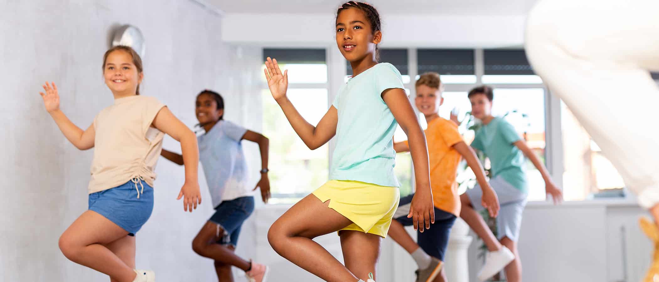 Energetic sporty african american tween girl practicing modern vigorous movements in group dance class ..